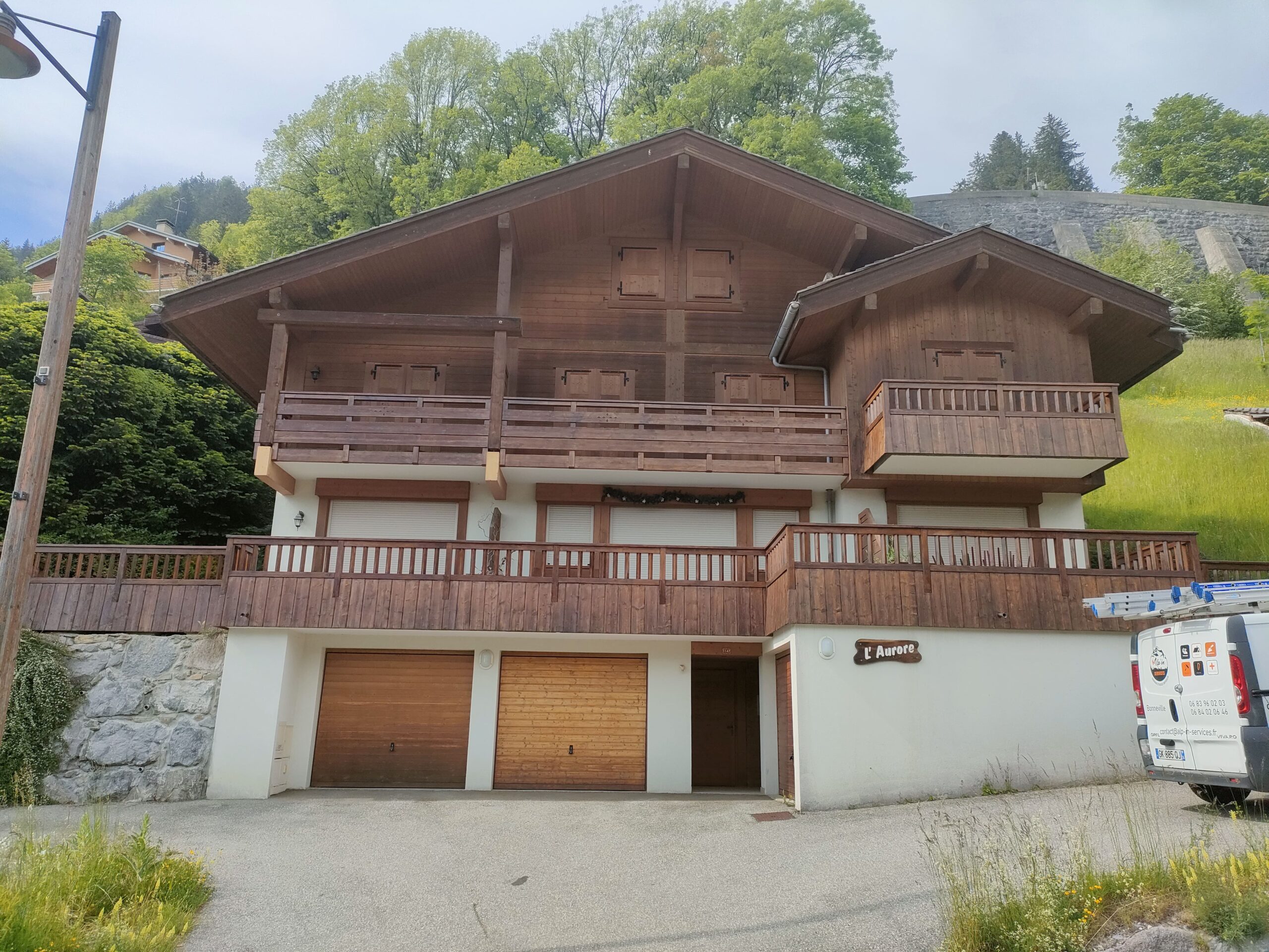 Façade d'un grand chalet en Haute-Savoie après travaux de peinture extérieure et application de lasure sur les boiseries et balcons.