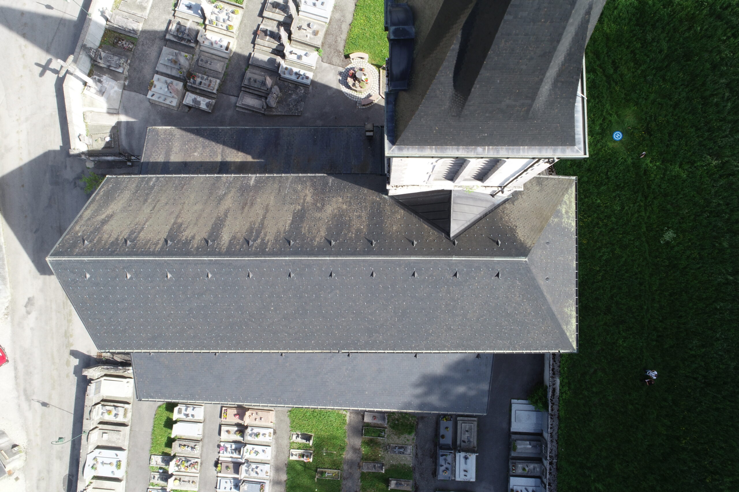 Vue aérienne d'une toiture d'église en ardoise et d'un cimetière, illustrant l'entretien du patrimoine pour les collectivités et communes.