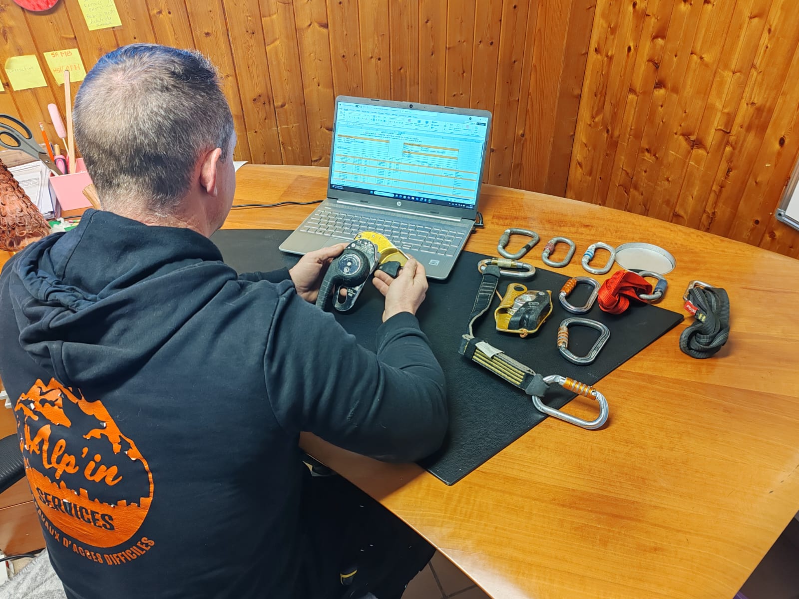 Technicien effectuant l'inspection visuelle d'équipements de sécurité (EPI) et la mise à jour du registre de maintenance sur ordinateur.