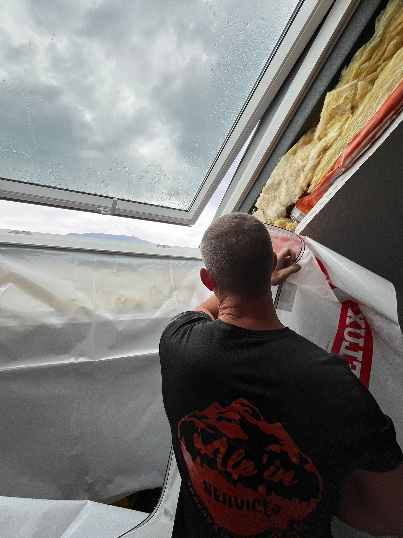 Technicien installant l'isolation intérieure et le pare-vapeur sur une fenêtre de toit Velux, garantissant l'étanchéité et la performance thermique.